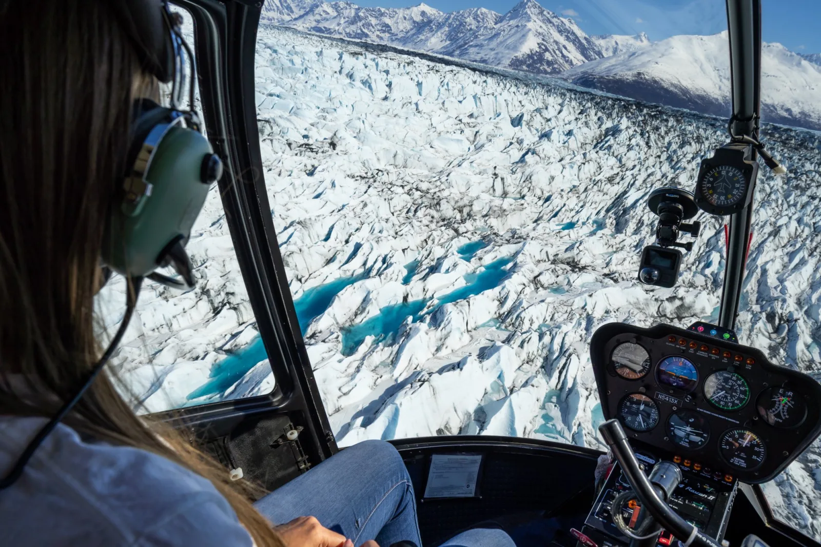 View from inside the helicopter over the crevasse field of Knik Glacier, the instrument panel lit in the foreground